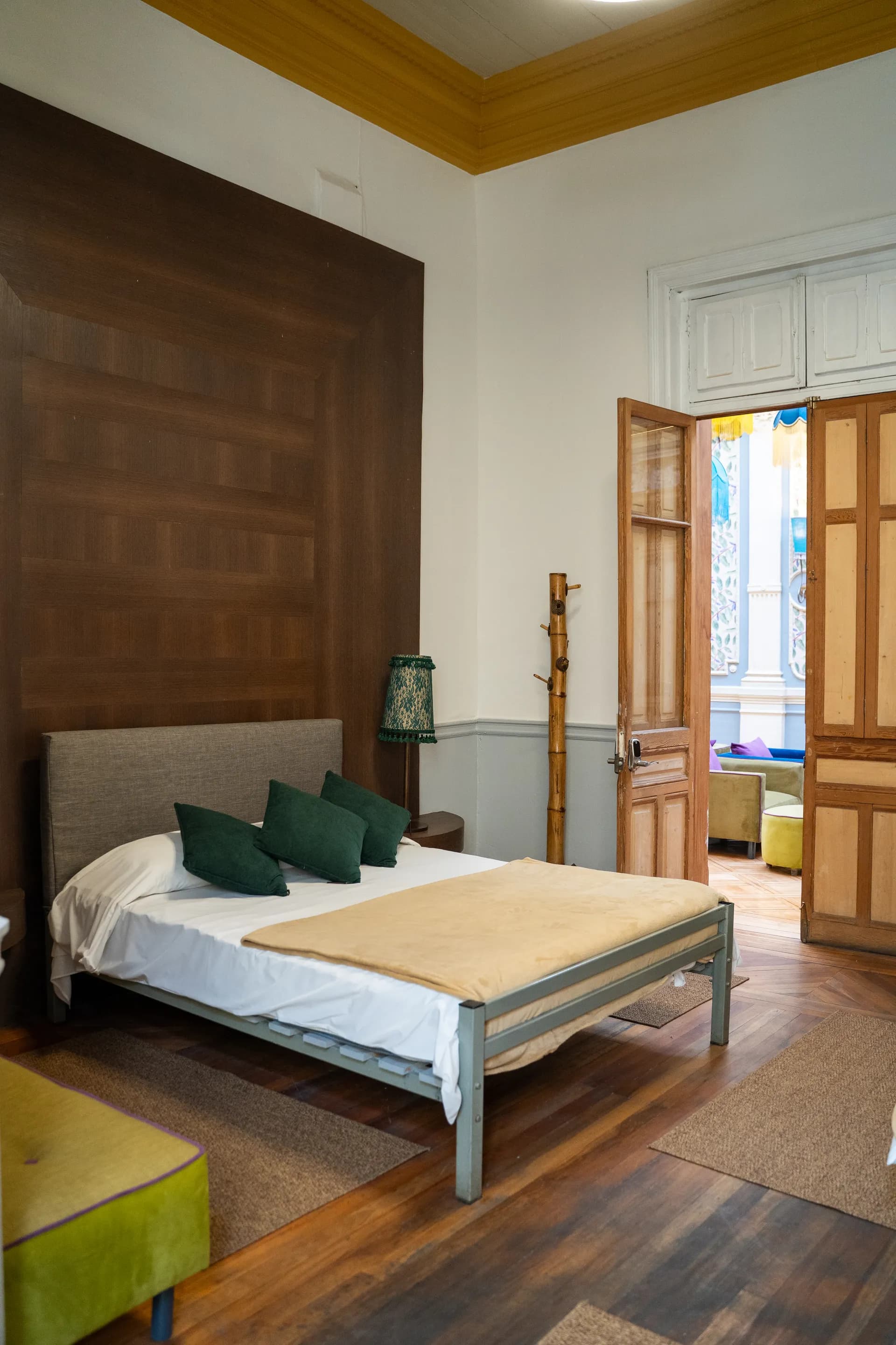 Spacious deluxe triple room at Happy Hostel Santiago for 3 guests with arched windows, geometric parquet and art deco details